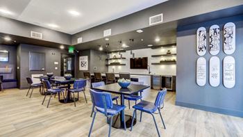 a dining room with blue chairs and tables and a kitchen